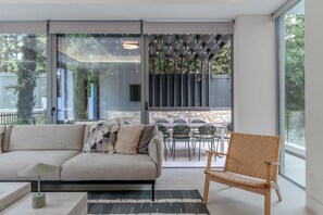 Ein modernes Wohnzimmer mit einer Couch, einer Holzbank und einem Essbereich mit Stühlen und einem Tisch.