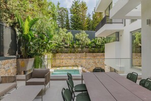 A modern outdoor patio with a pool, stone walls, and lush greenery. - Private Pool Villa | Walk to Beach & Voula Square (Voula)
