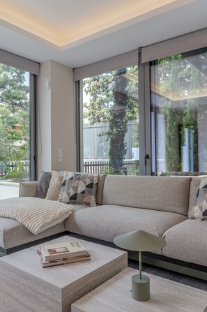 A modern living room with a sofa, a coffee table, and a lamp. - Private Pool Villa | Walk to Beach & Voula Square (Voula)