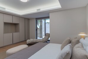 A modern bedroom with a bed, a chair, a bedside table, and a lamp.