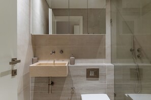 A modern bathroom with a rectangular sink, a mirror, a shower, and a toilet.
