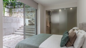 A bedroom with a bed, pillows, a nightstand, a lamp, and a sliding door leading to a bathroom.