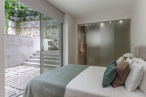 Ein Schlafzimmer mit Bett, Kissen, einem Nachttisch, einer Lampe und einer Schiebetür zu einem Badezimmer.