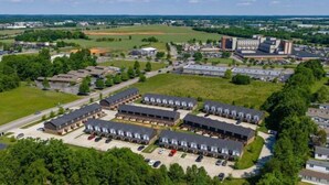 An aerial view of a campus with multiple buildings, parking areas, and green spaces. - Bright, Modern 2 bedroom Home Away From Home (Clarksville)
