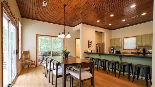 A modern kitchen with wooden cabinets, a central island, and bar stools. - Pool table, hot tub, indoor sauna, outdoor spaces, big kitchen in Gatlinburg! (Gatlinburg)