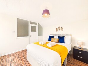 Ein Hotelzimmer mit Bett, Nachttisch, Lampe, Tür und Fenster.