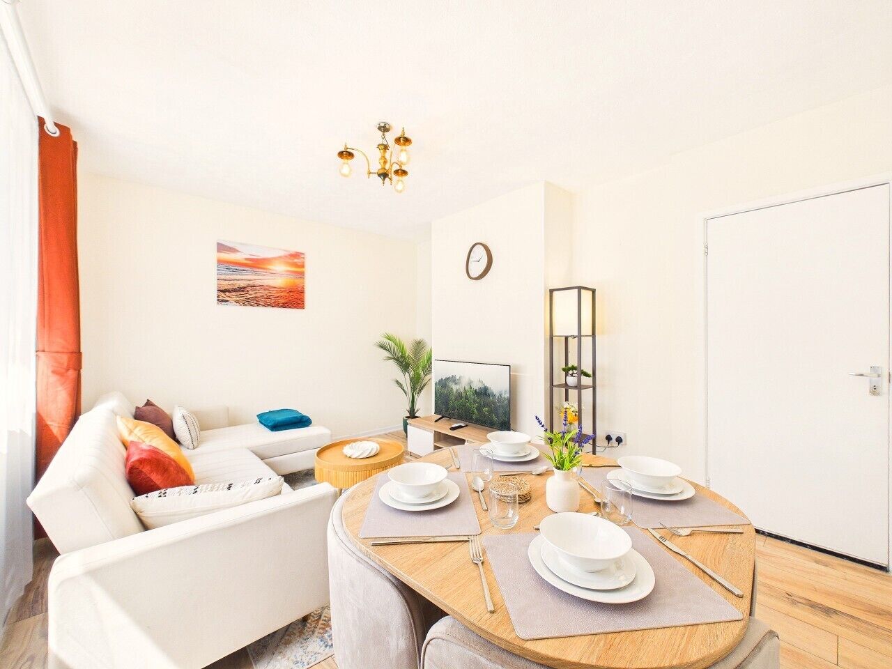 A modern living room with a dining area, a sofa, a TV, and a clock on the wall.
