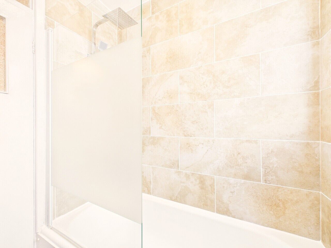 A bathroom with a shower, tiled walls, and a bathtub.