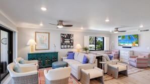 A living room with a sofa, chairs, a television, and artwork on the walls. - Sea Oats 117 | 2BR/2BA Boca Grande Gulf Front Luxe (Boca Grande)