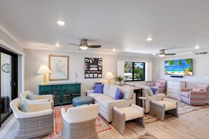 Ein Wohnzimmer mit einer Couch, Sesseln, einem Fernseher und Kunstwerken an den Wänden.