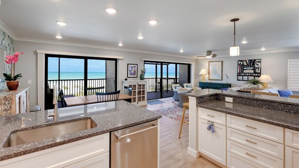 A spacious kitchen with a large island, a dining area with a view of the ocean, and a balcony with a railing. - Sea Oats 117 | 2BR/2BA Boca Grande Gulf Front Luxe (Boca Grande)