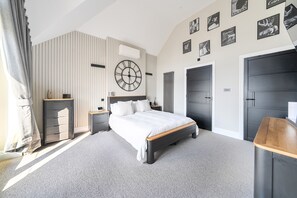 A bedroom with a bed, bedside tables, a wall clock, and a wardrobe.