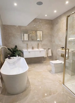 A modern bathroom with a freestanding bathtub, a glass-enclosed shower, and a large mirror above the vanity.