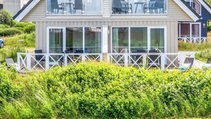 Ein modernes, zweistöckiges Haus mit großen Fenstern, einem Balkon und einem weißen Zaun.