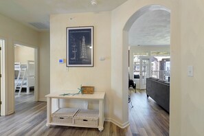 A living room with a white console table, wicker baskets, a framed architectural drawing, and a grey sofa.