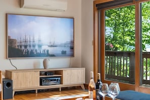 Ein Wohnzimmer mit einem großen Flachbildfernseher, einer Holzunterhaltungsecke und einem Essbereich mit Weingläsern.