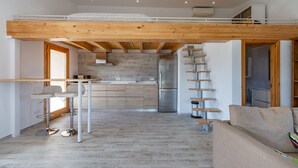 A modern kitchen with a central island, a dining area with a table and chairs, and a lofted sleeping area with a wooden ceiling. - VERY QUIET COUNTRY HOUSE NEAR INCA (Inca)