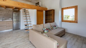 A modern living space with a kitchen, a sofa set, a wooden loft, and a window with a view. - VERY QUIET COUNTRY HOUSE NEAR INCA (Inca)