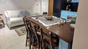 Un comedor con una mesa, sillas, un tazón de comida y un refrigerador al fondo.