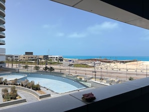 Una piscina amb vora corba, una platja al fons i un cel serè.