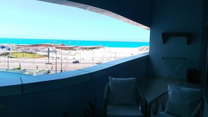 Una habitación con ventanal curvo que da a una playa y un estacionamiento.