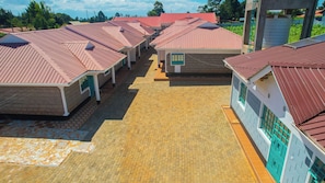 A row of small, single-story buildings with red roofs, arranged in a linear fashion on a paved ground.