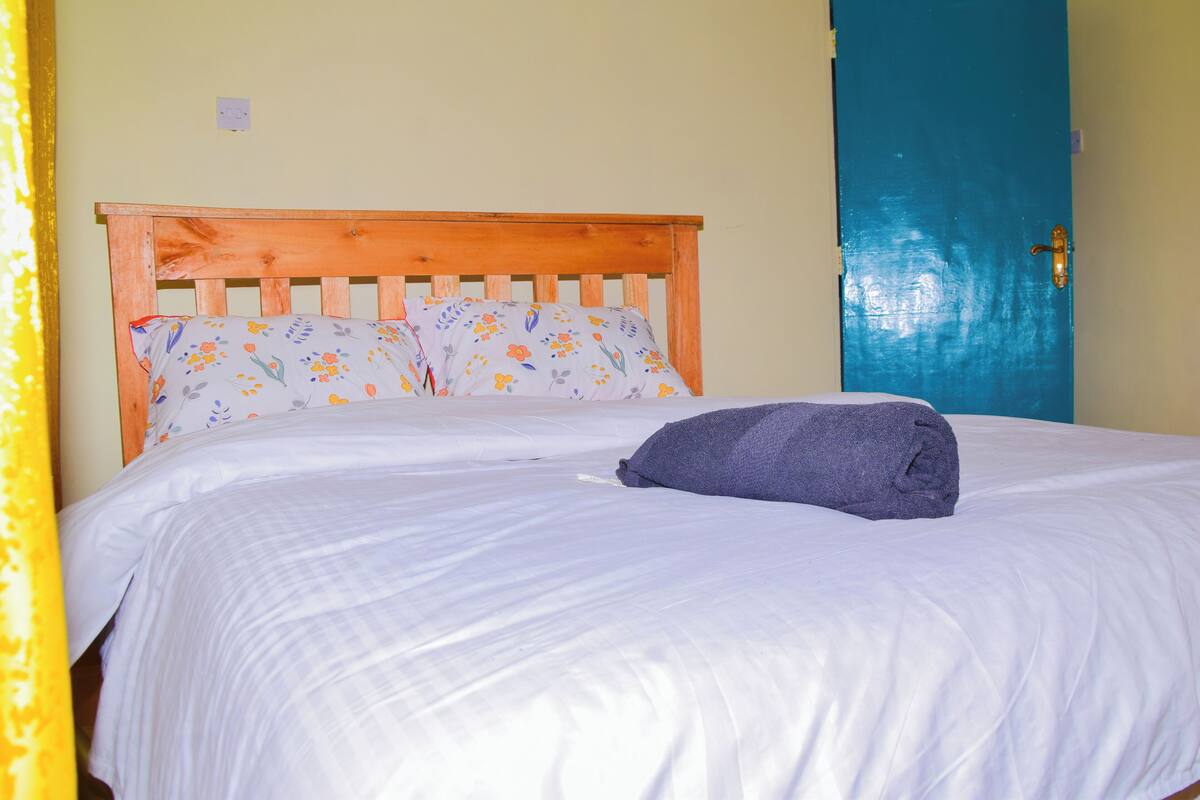 A bed with a wooden headboard, white bedding, and a blue door in the background.