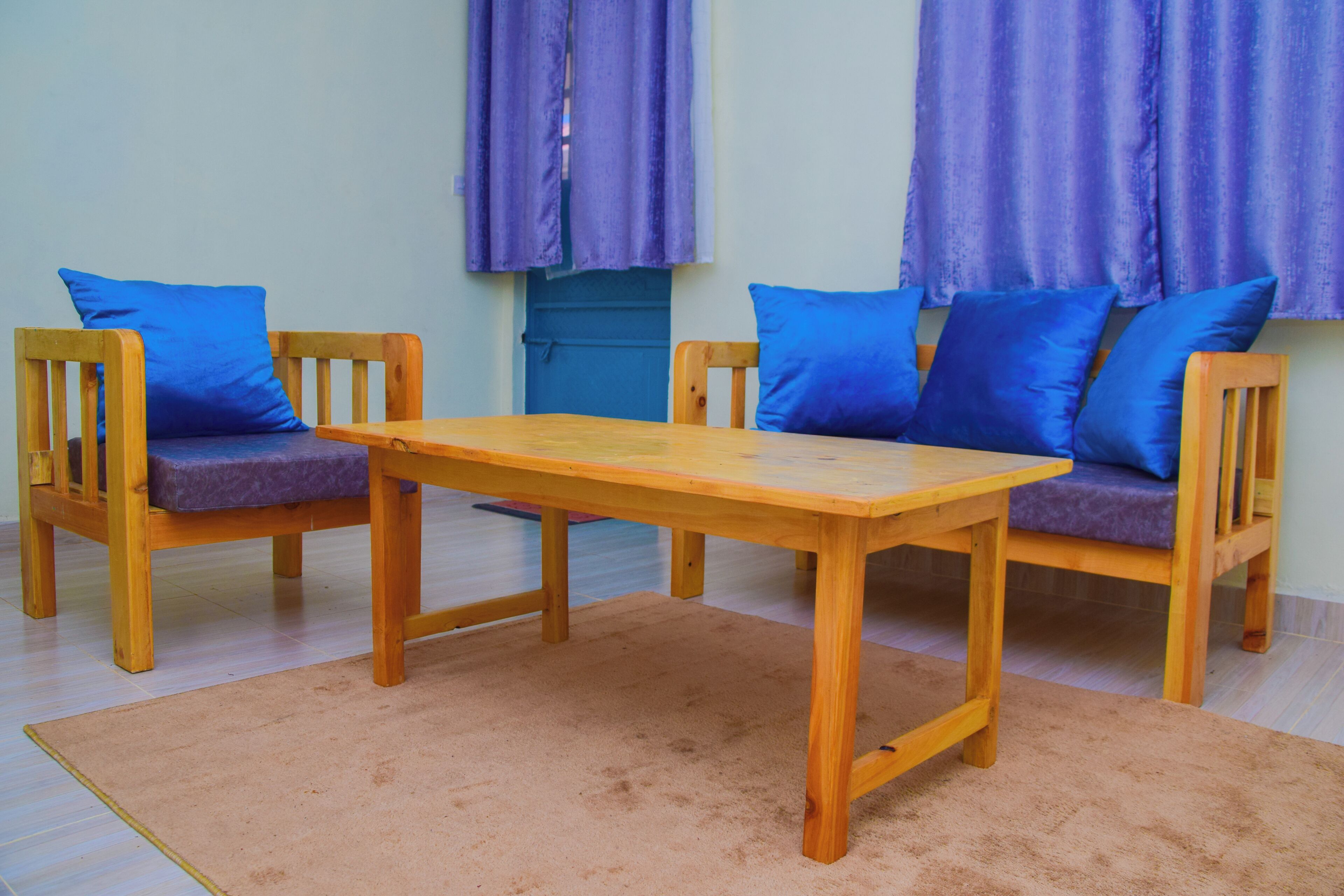 Ein Zimmer mit einem Holztisch und zwei Stühlen mit blauen Kissen.