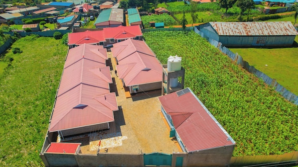A large building with multiple red-roofed sections, surrounded by green fields and a fenced area.