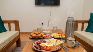 Une table de petit-déjeuner avec des œufs, du bacon, des toasts, des haricots et un thermos.