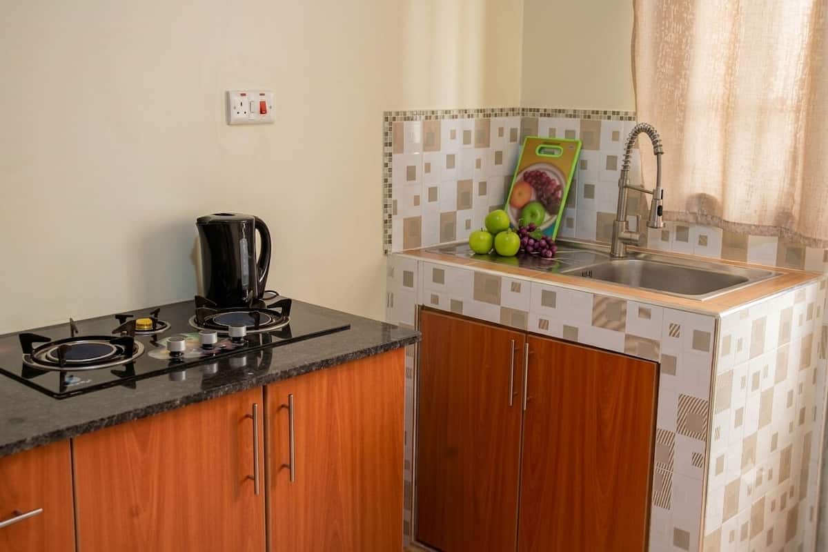 A compact kitchen with a gas stove, a coffee maker, a sink, and a tiled backsplash.