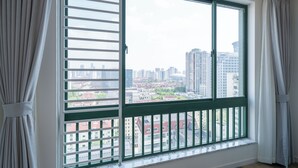 A room with a large window, curtains, and a view of a cityscape. - Tyms 2BR 1BA Family Serviced Residence (Shanghai)
