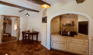 Une cuisine avec une table en bois, un luminaire suspendu et un four Ă micro-ondes placĂ© au-dessus dâune porte.
