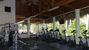 A gym with exercise equipment, a ceiling fan, and a view of palm trees. - All inclusive paid at the resort  (Puerto Plata)