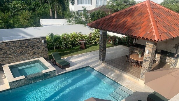 A swimming pool with a hot tub, lounge chairs, and a covered patio area. - All inclusive paid at the resort  (Puerto Plata)