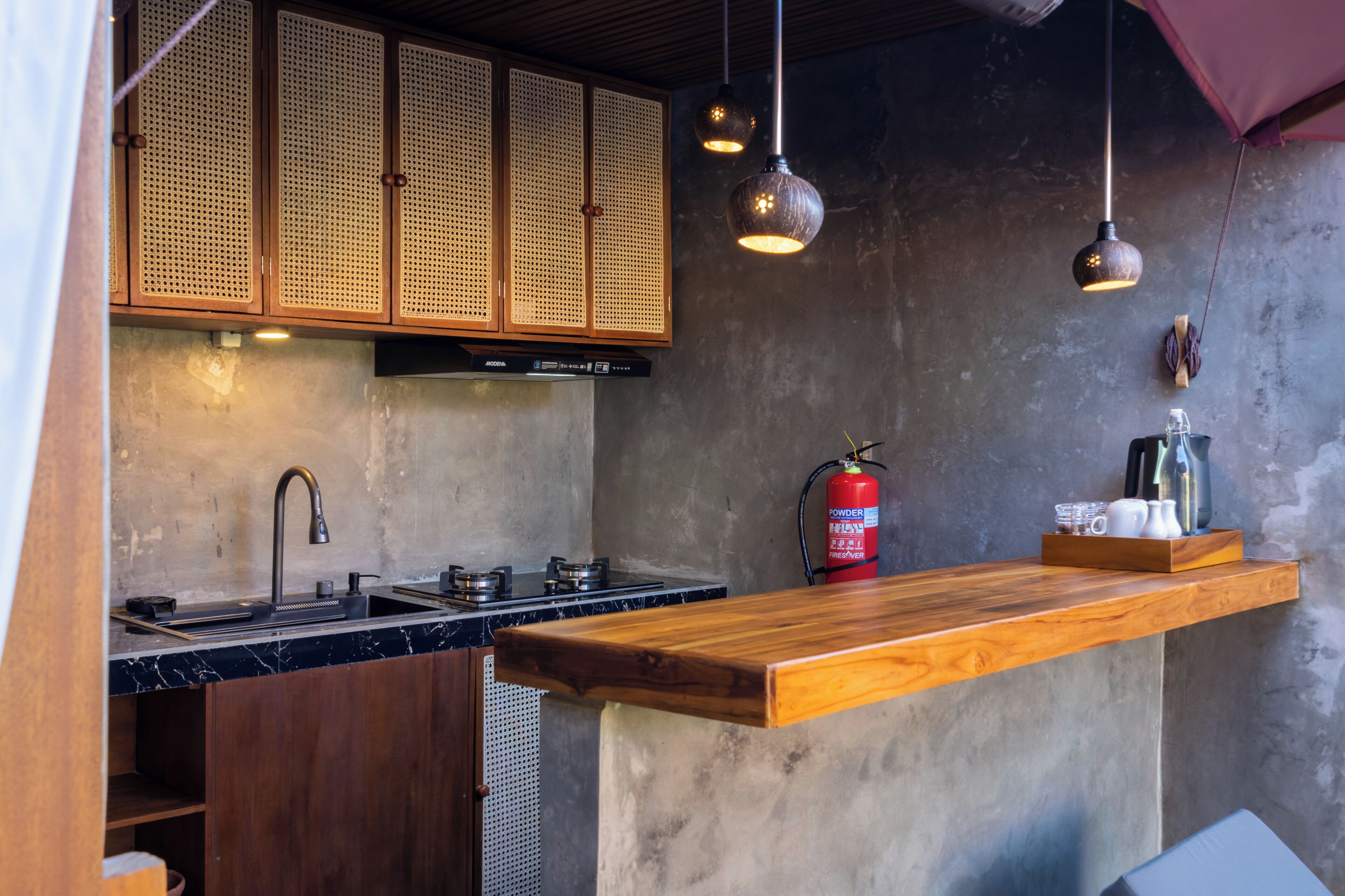 Una cucina con un piano di lavoro in legno, un lavello, un fornello e un estintore.