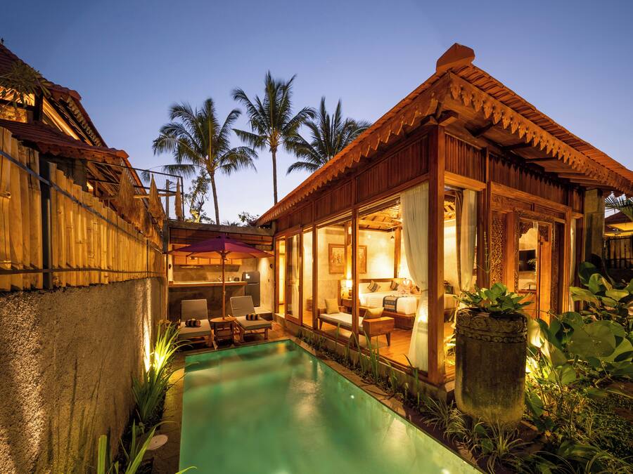A poolside area with a wooden deck, a lounge chair, and a small table.