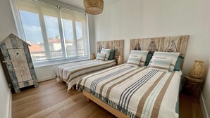 Ein Schlafzimmer mit einem großen Bett, einem Fenster, einem Holzschrank und einer Pendelleuchte.