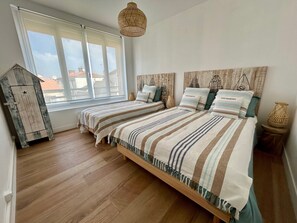Ein Schlafzimmer mit einem großen Bett, einem Fenster, einem Holzschrank und einer Pendelleuchte.