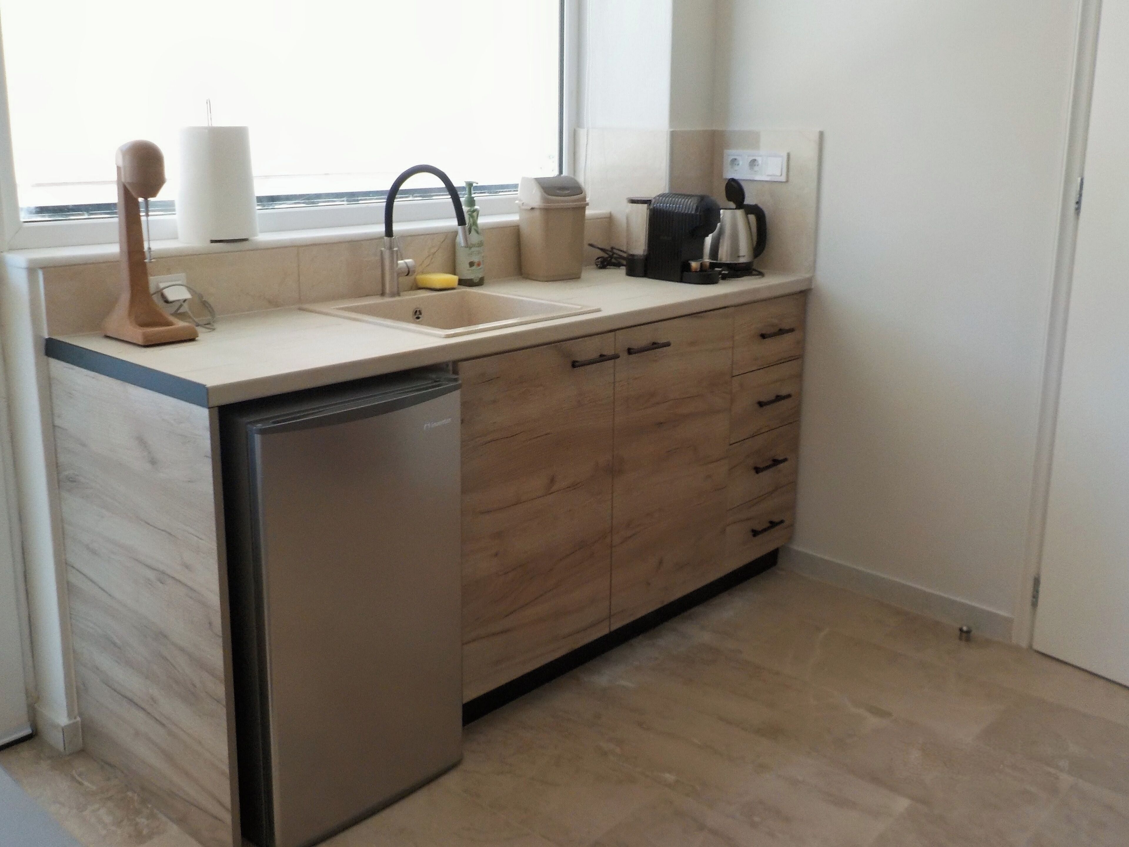 Una cocina moderna con lavavajillas, pileta y muebles de madera.