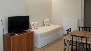 Een kamer met een bed, een televisie op een houten kast, een tafel en stoelen.