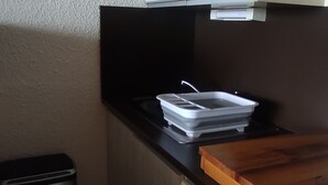 Una cocina con encimera negra, un cubo de basura y una tabla de cortar de madera.