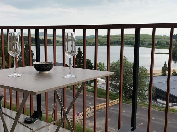 A balcony with a table, two wine glasses, and a bowl. - Comfortable studio, 4 guests, Super Besse center (Besse-et-Saint-Anastaise-Super Besse)