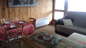 Una habitación con una mesa de comedor dispuesta con platos y vasos, un sofá, un radiador y un cuadro de osos en la pared.