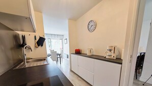 Una cocina moderna con un lavamanos de acero inoxidable, una cafetera y un reloj en la pared.