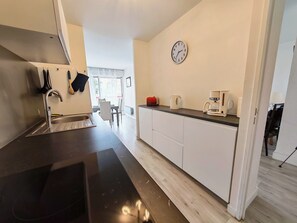 A modern kitchen with a stainless steel sink, a coffee maker, and a clock on the wall. - T3 Apartment with parking, sea & mountain view (Canet-en-Roussillon)