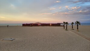 Una playa con una cerca de madera, palmeras y un letrero que dice 'Kiara'.
