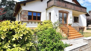 Une maison à deux étages dotée d’un balcon, d’une porte d’entrée et d’un escalier menant à l’entrée.