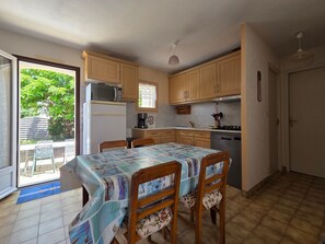 A compact kitchen with wooden cabinets, a microwave, a refrigerator, and a dining table with chairs. - Residential house, pets on request - 4 guests (Grues)