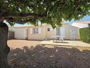 A house with a patio, a table with chairs, and a tree in the foreground. - Residential house, pets on request - 4 guests (Grues)